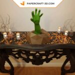 Papercraft of a hand emerging from the ground in 3D origami