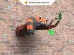 Papercraft panda rosso addormentato su un ramo in origami 3D, montato