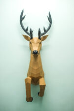 Papercraft deer emerging from wall in 3D origami