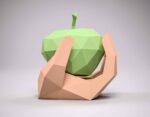 Mano de papel sosteniendo una manzana de origami en 3D