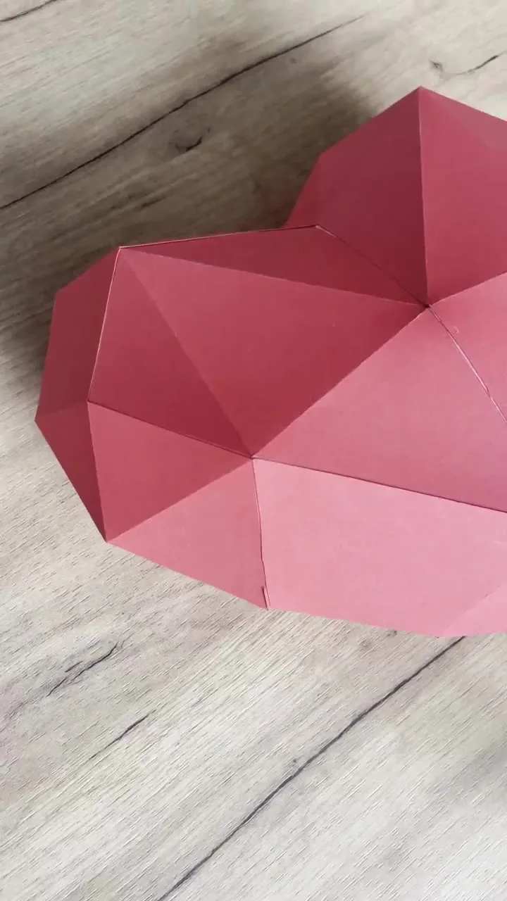 Cœur rouge géométrique posé sur une table en bois