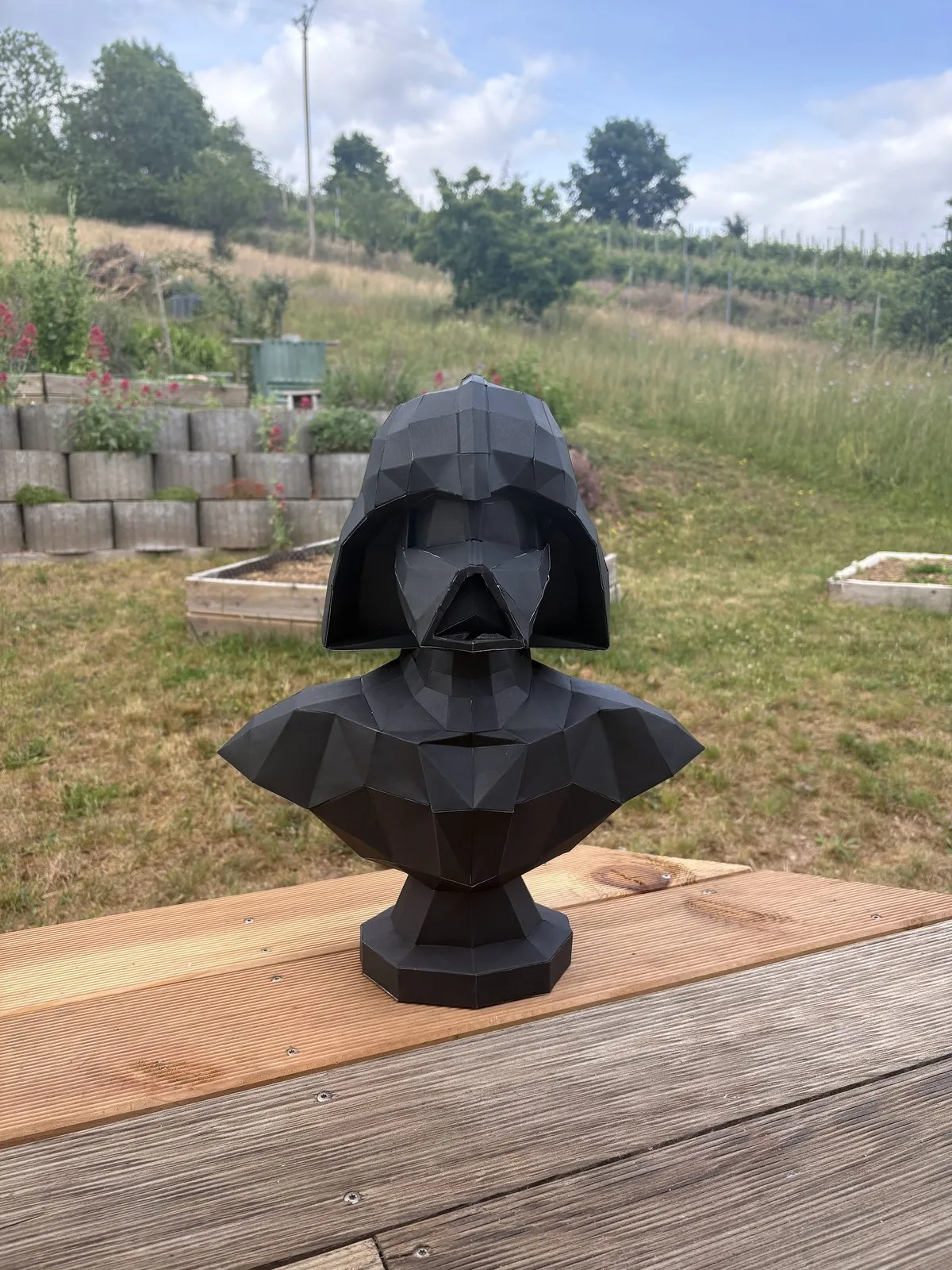 Buste de Dark Vador noir posé sur terrasse en bois clair