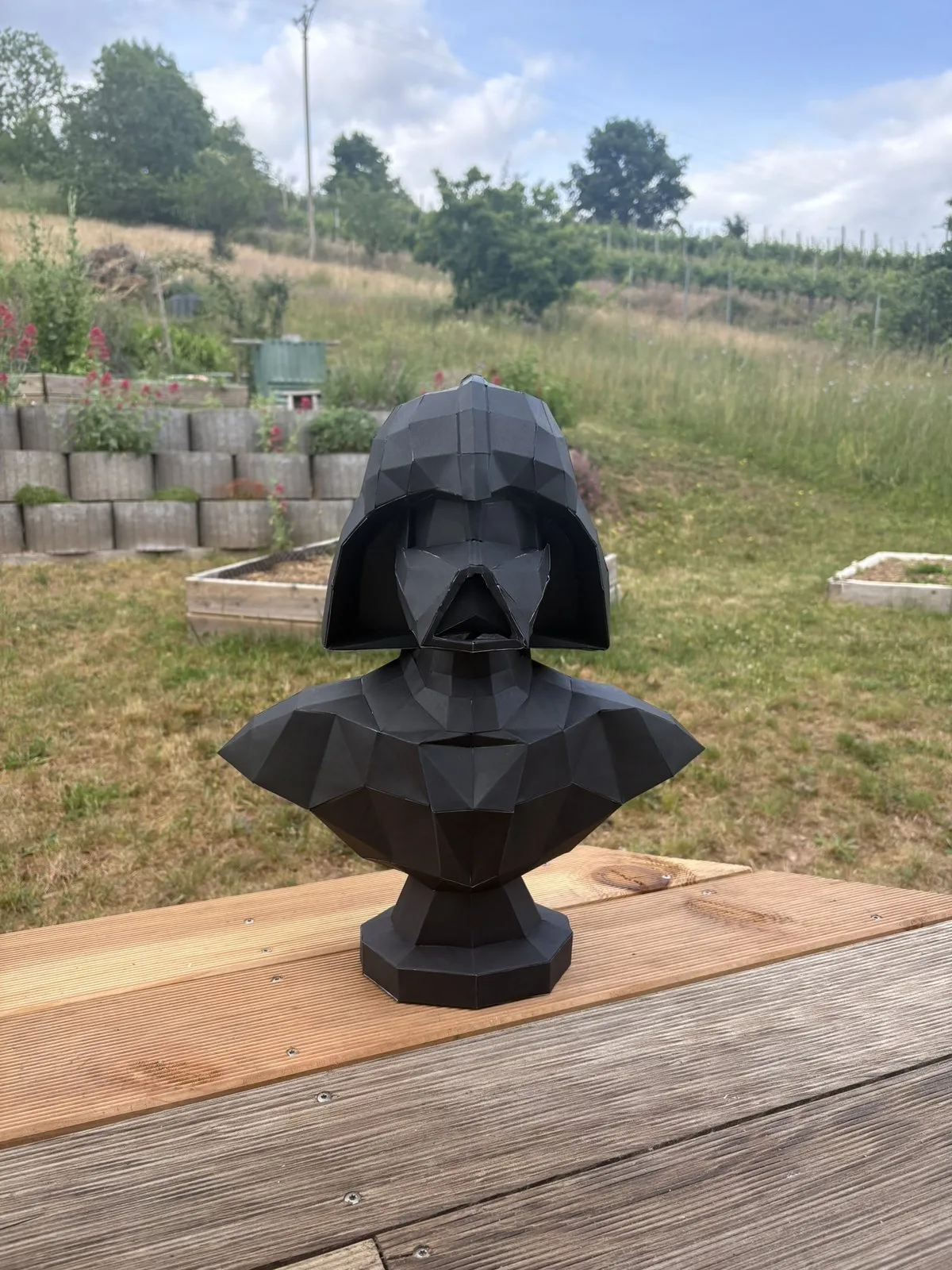 Tête de Dark Vador noir trônant sur table de jardin en bois