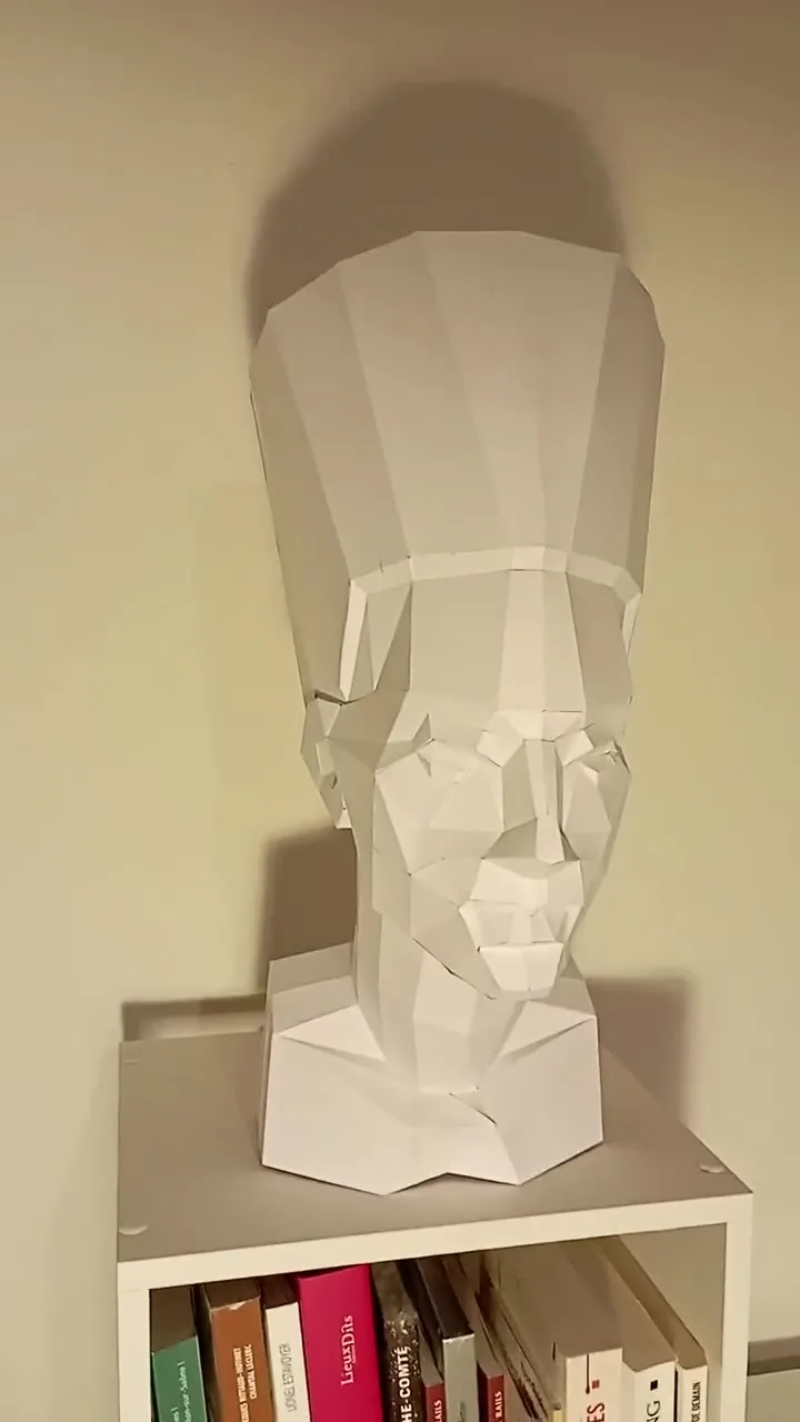 Buste de Néfertiti en papercraft blanc posé sur une étagère
