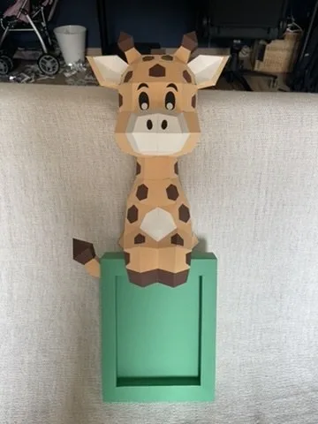 Girafe en papier posée sur un cadre photo vert