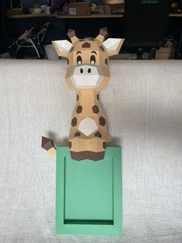 Cadre vert surmonté d’une girafe mignonne en papier