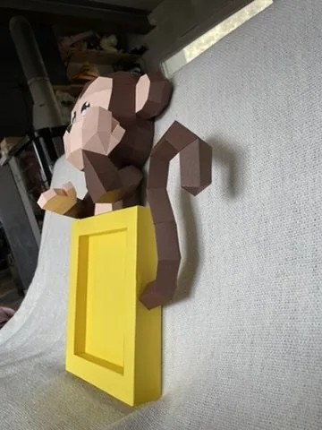 Singe marron en papercraft fixé à un cadre mural