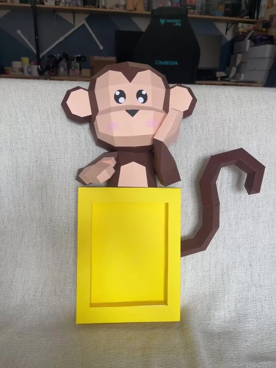 Singe en papier souriant devant un cadre jaune