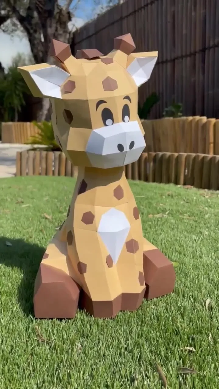 Bébé girafe assise aux taches marron sur pelouse ensoleillée