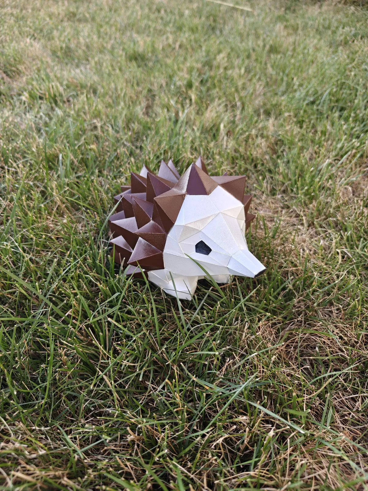 Hérisson en papercraft brun et blanc posé dans l'herbe