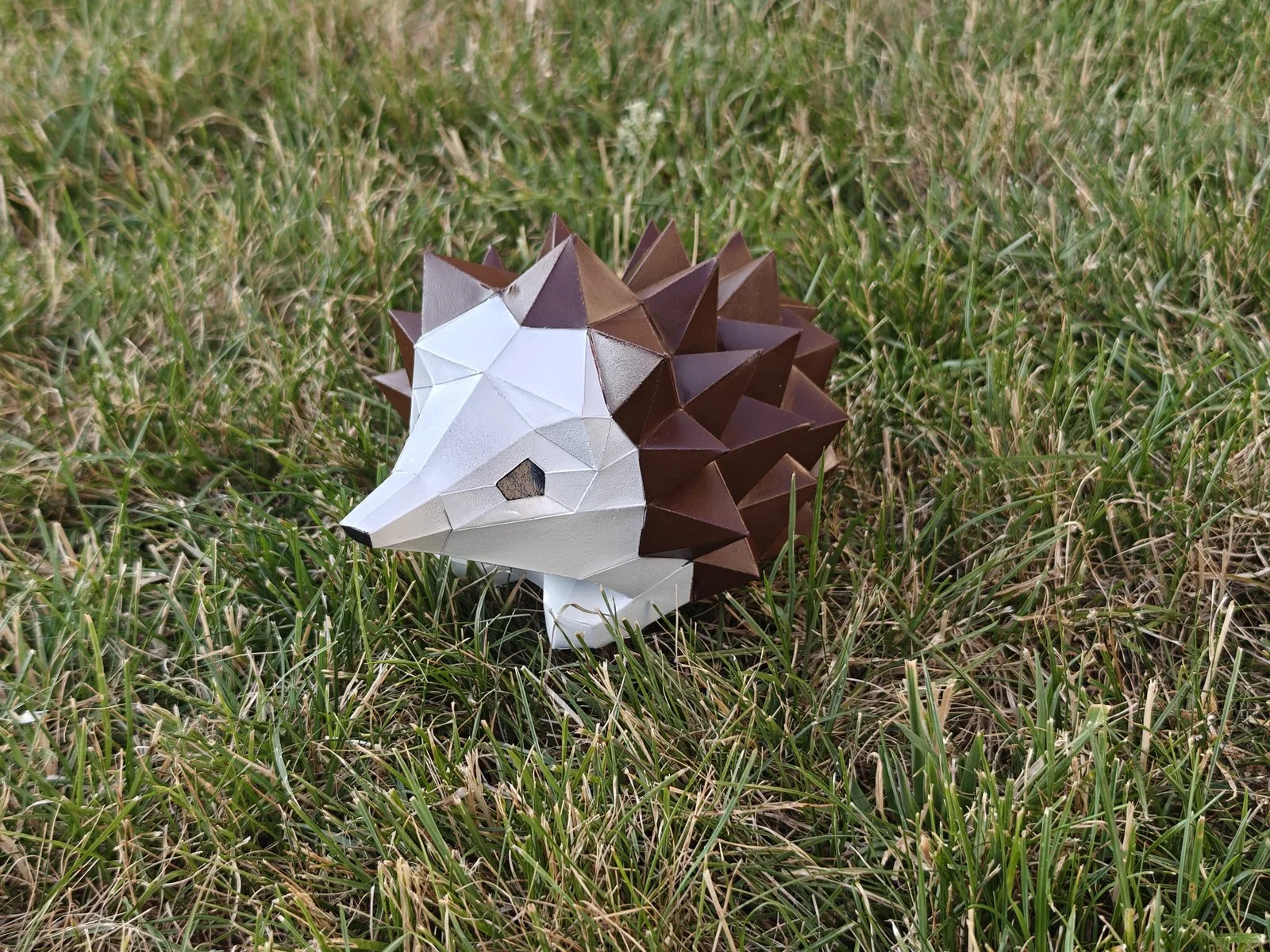 Hérisson en papercraft vu de profil dans l'herbe sèche