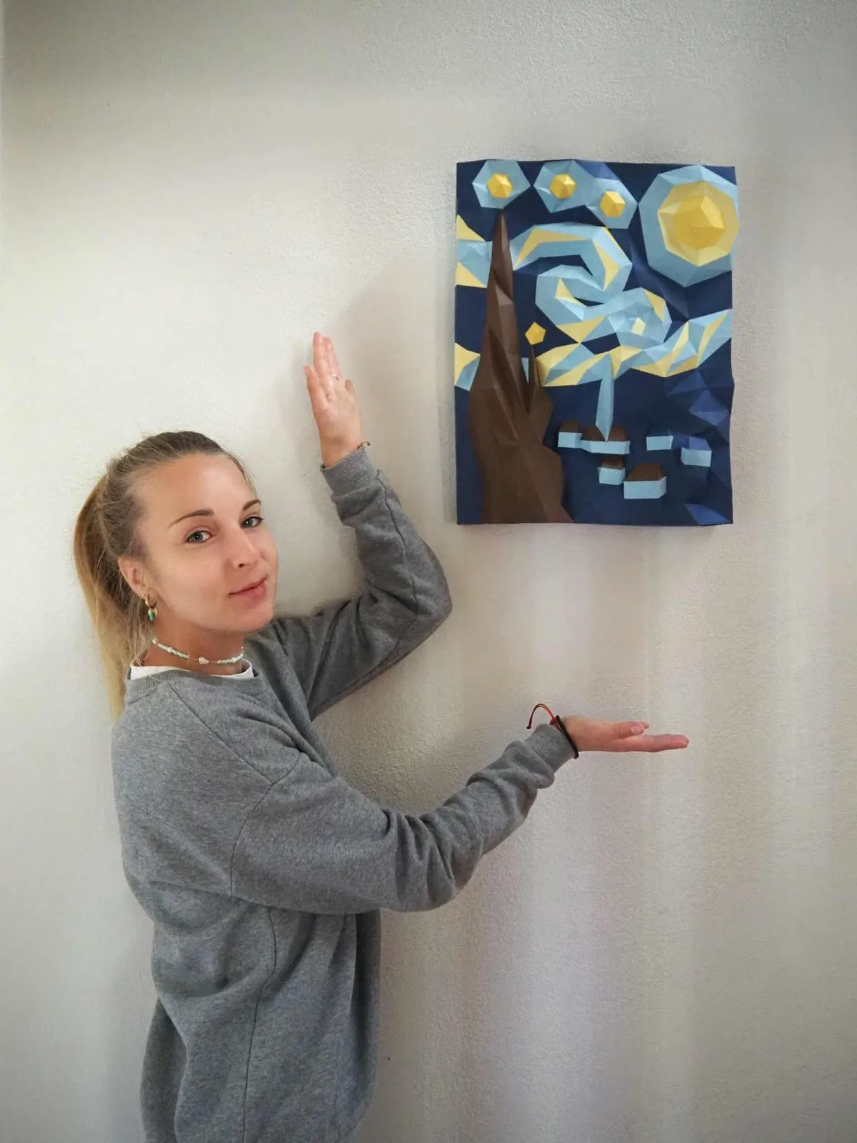 Femme présentant fièrement le tableau mural Nuit étoilée de Van Gogh en papercraft bleu/jaune accroc