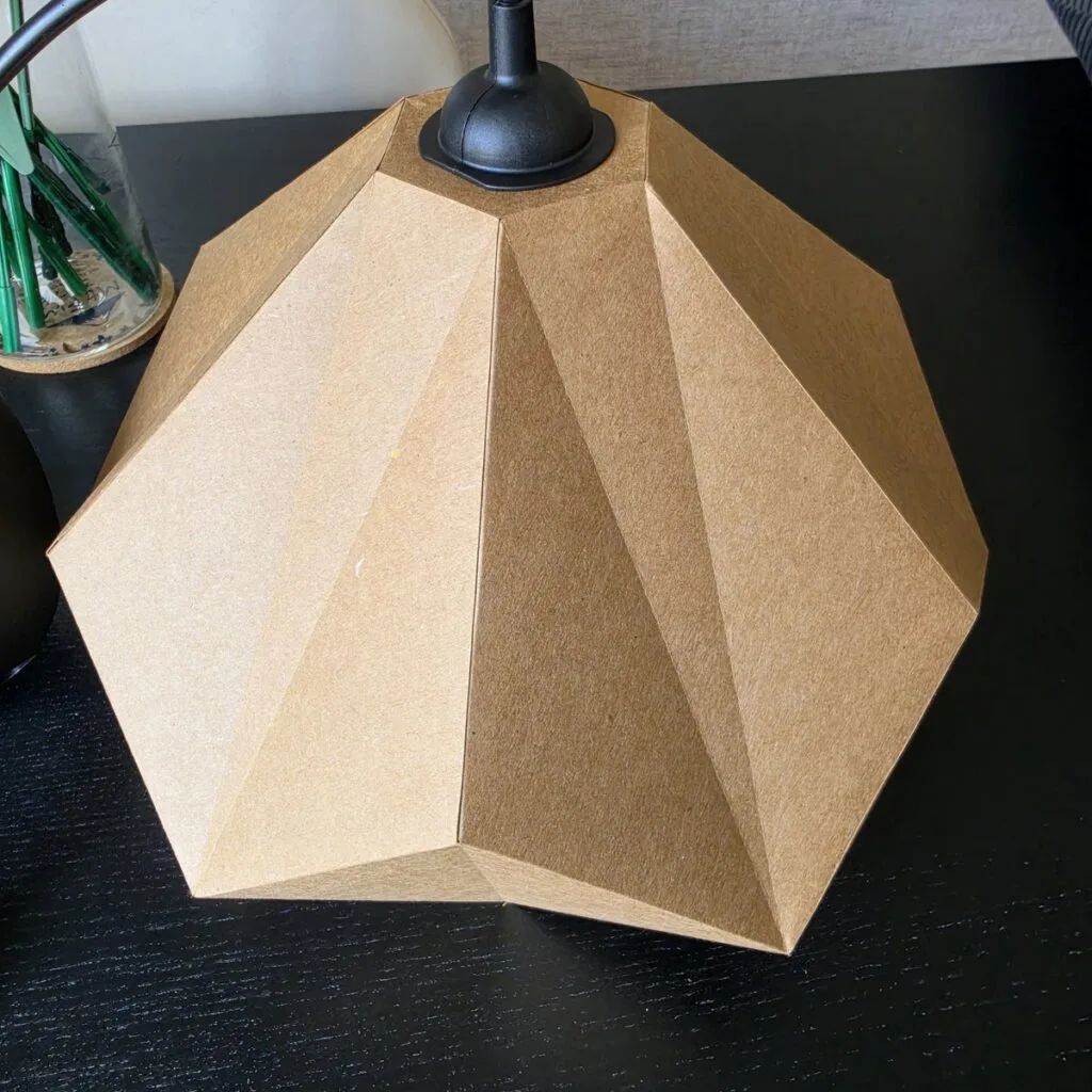 Lampe solstice en papier kraft posée sur table noire