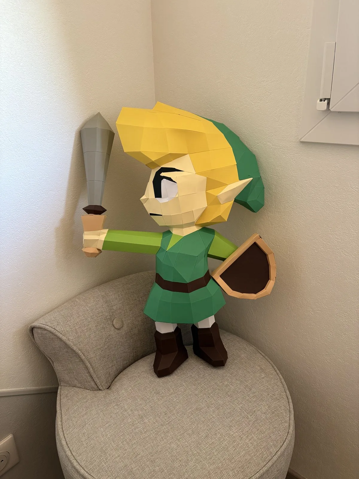 Link brandissant son épée et bouclier sur un fauteuil