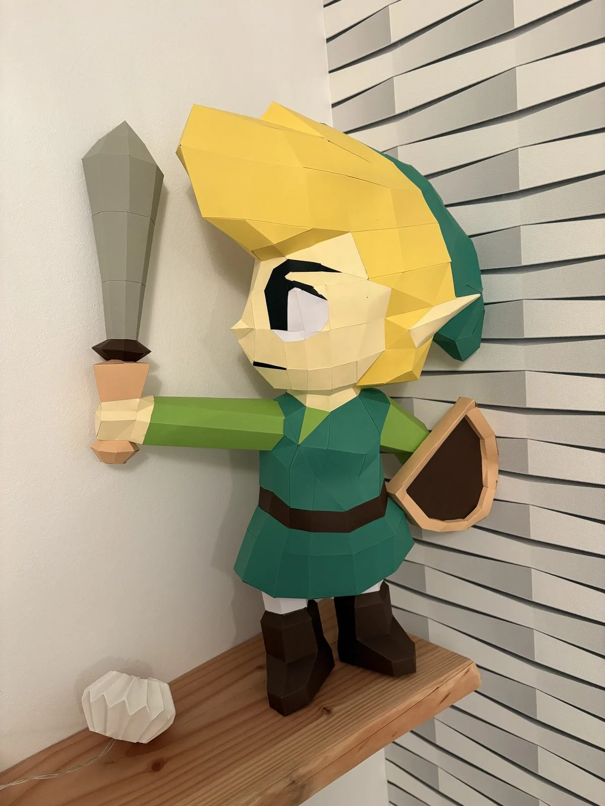 Link en papercraft près d’une sphère LED sur étagère en bois