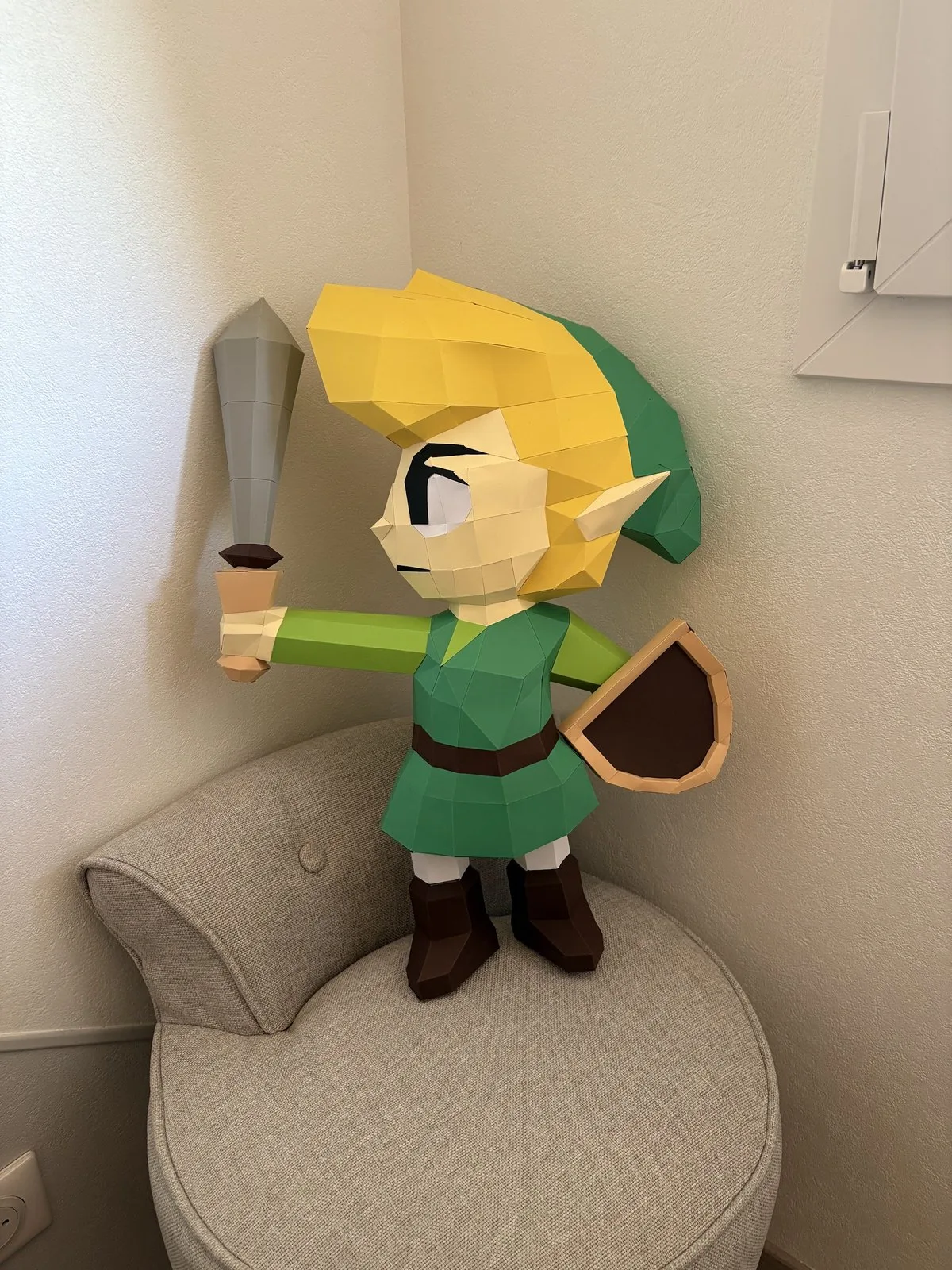 Figurine de Link avec épée levée et bouclier sur fauteuil