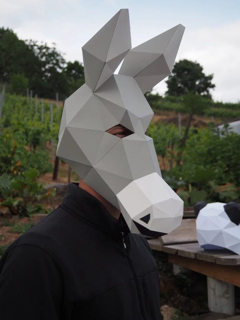 Masque d’âne gris posé devant un masque de panda en papier