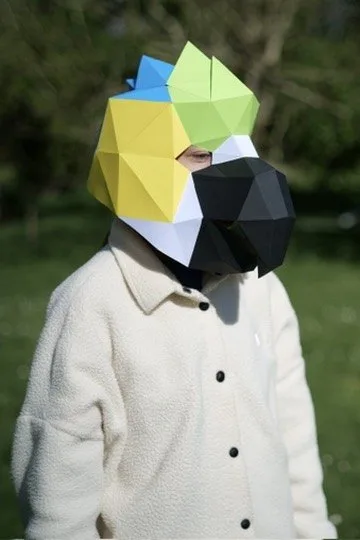 Enfant masqué en perroquet coloré aux plumes vertes et bleues