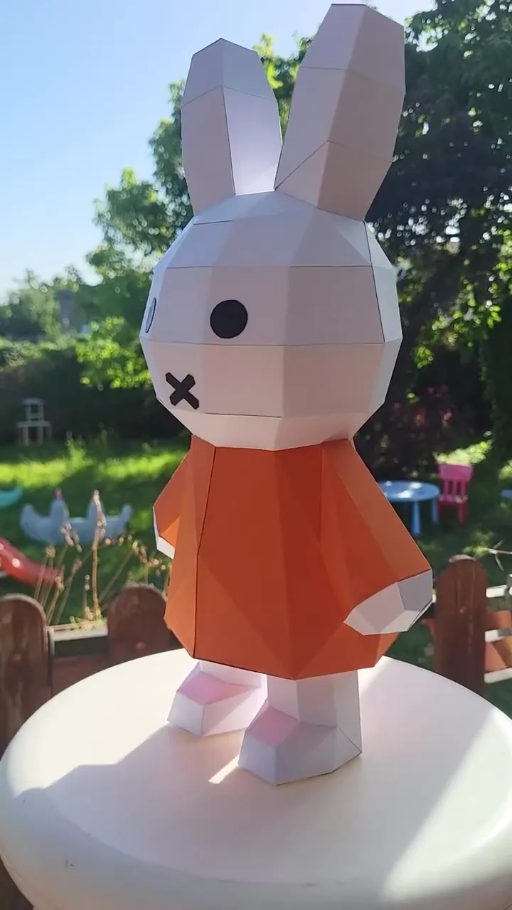 Lapin Miffy en papercraft posé sur un support blanc dans un jardin