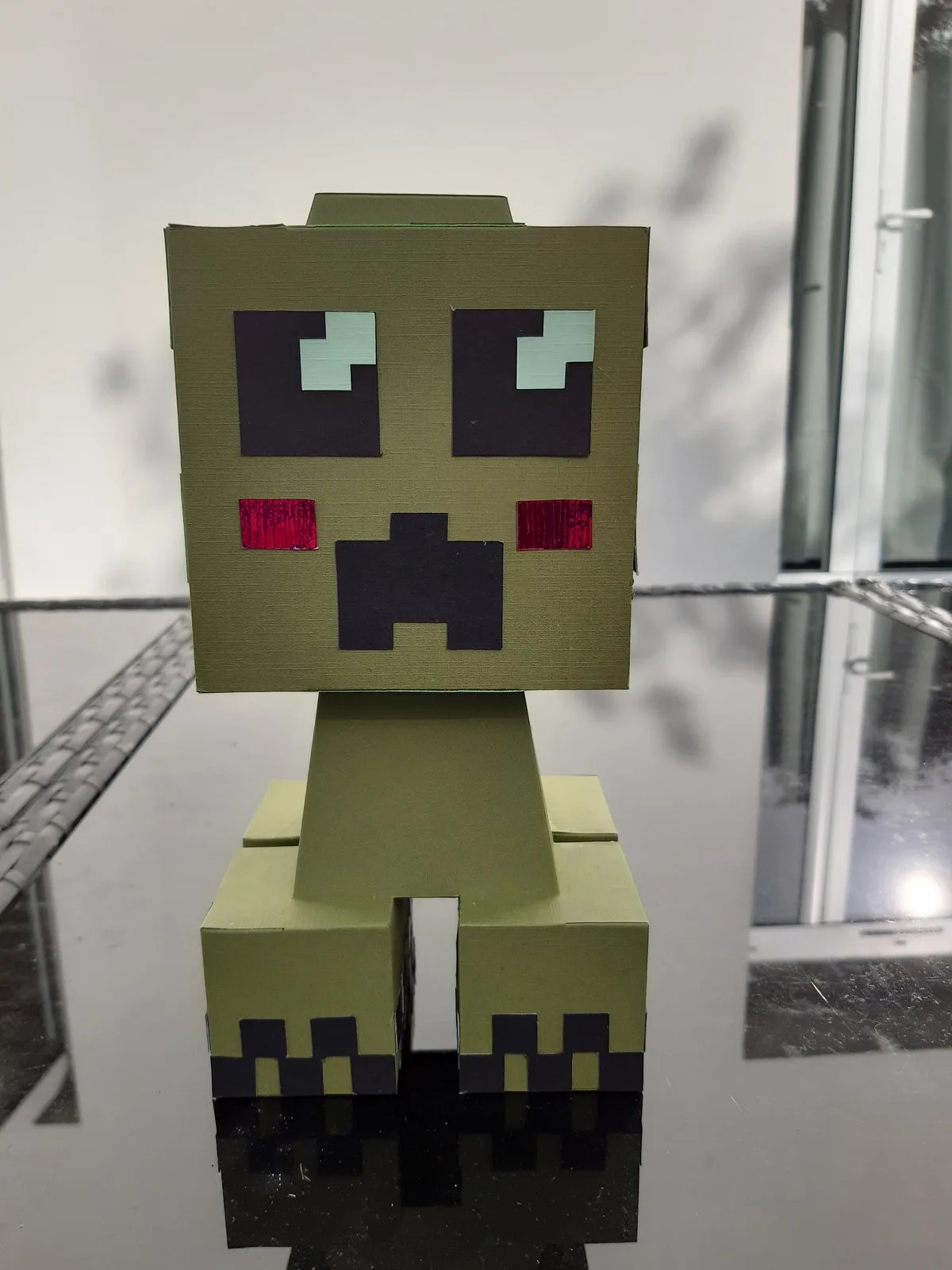 Personnage Minecraft en papercraft vu de face, tête cubique en damier vert