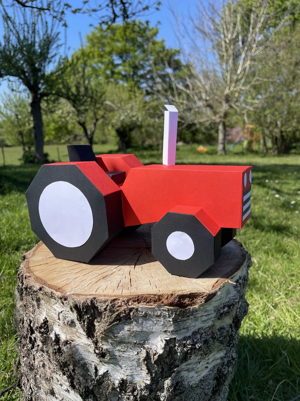 Tracteur rouge et noir miniature dans jardin ensoleillé