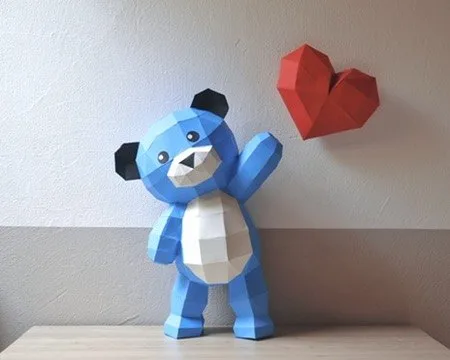 Ours en peluche bleu saluant avec cœur rouge accroché au mur