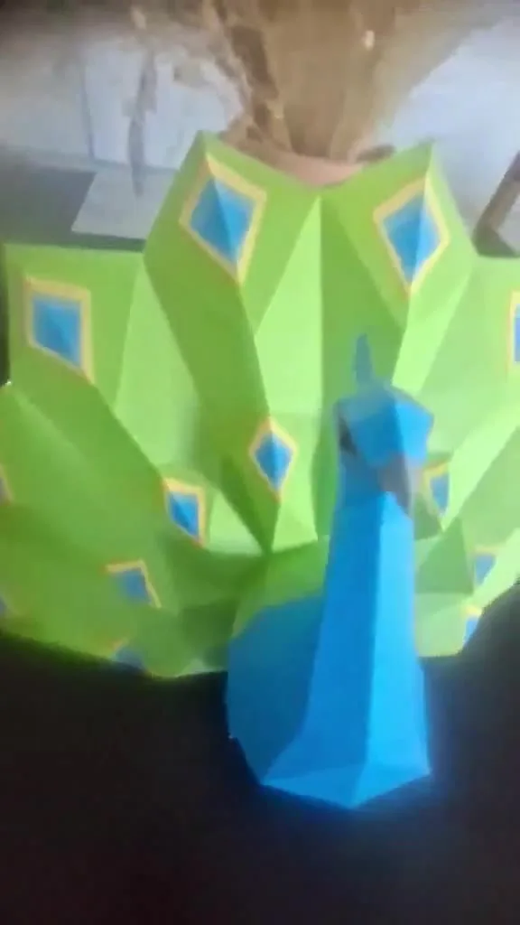 Paon en papercraft posé sur une table sombre