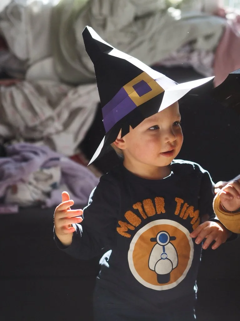 Enfant avec chapeau de sorcière noir à bande violette et boucle dorée