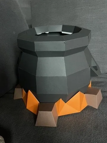 Photo client : chaudron noir sur flammes orange, couvercle/potion pas encore posés (montage en cours