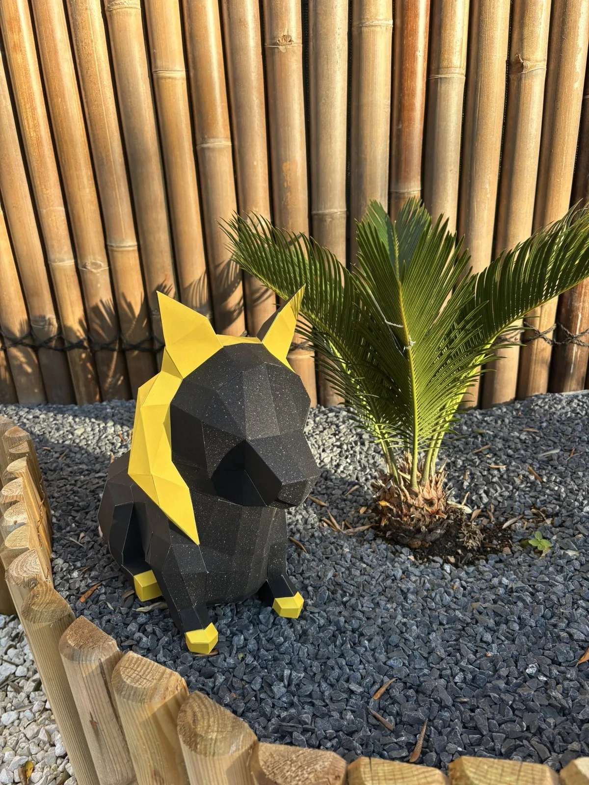 Chien papercraft noir et or devant des bambous