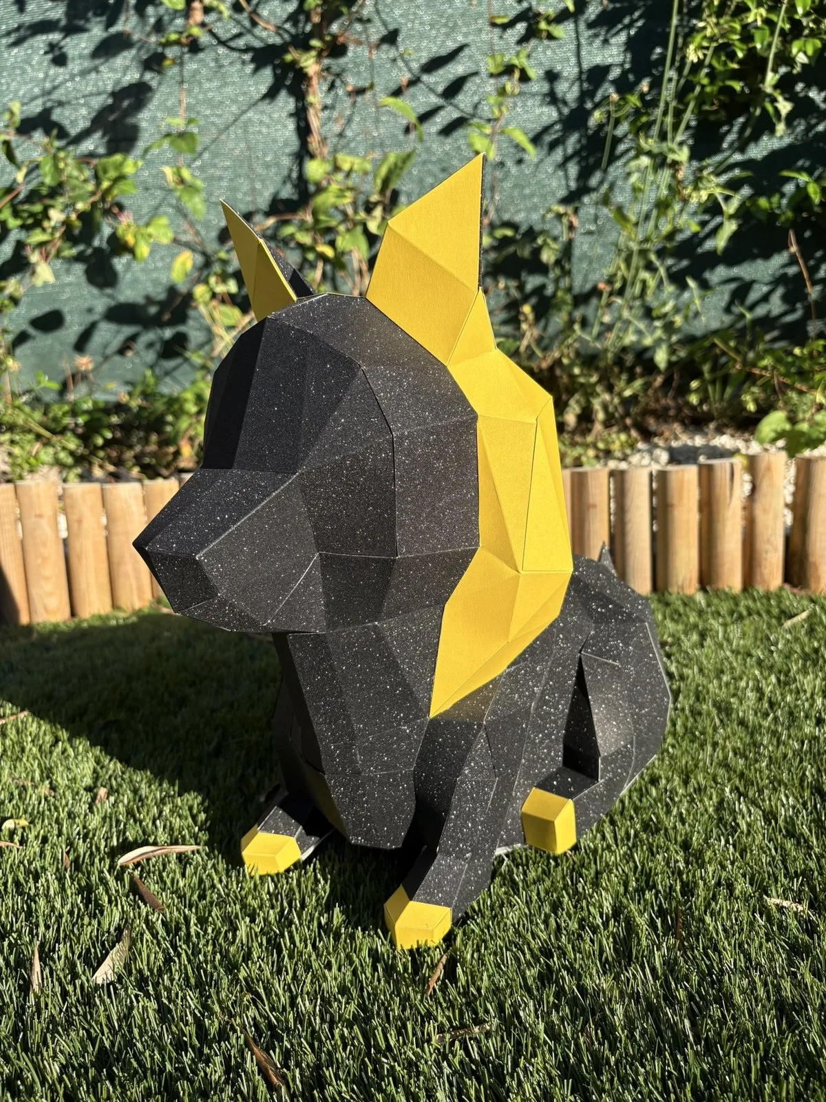 Chien en papier assis sur l’herbe en trois-quarts