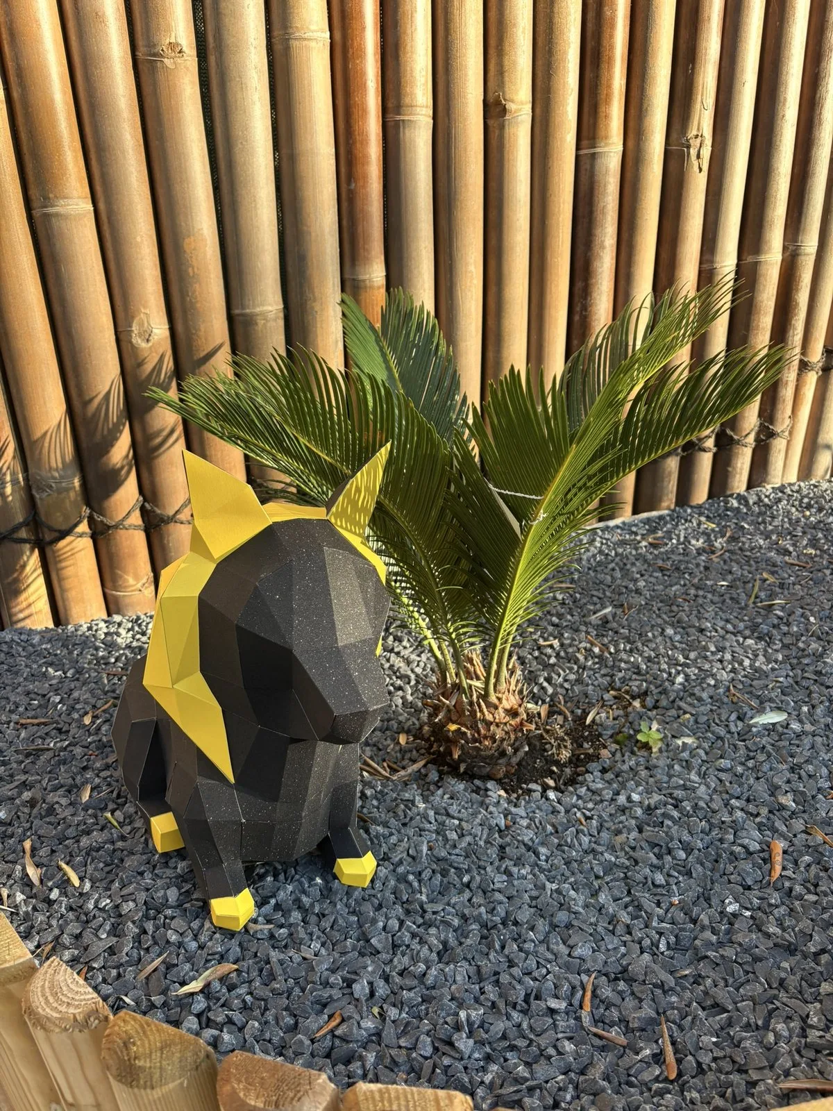Chien noir et doré posé sur gravier près de plantes