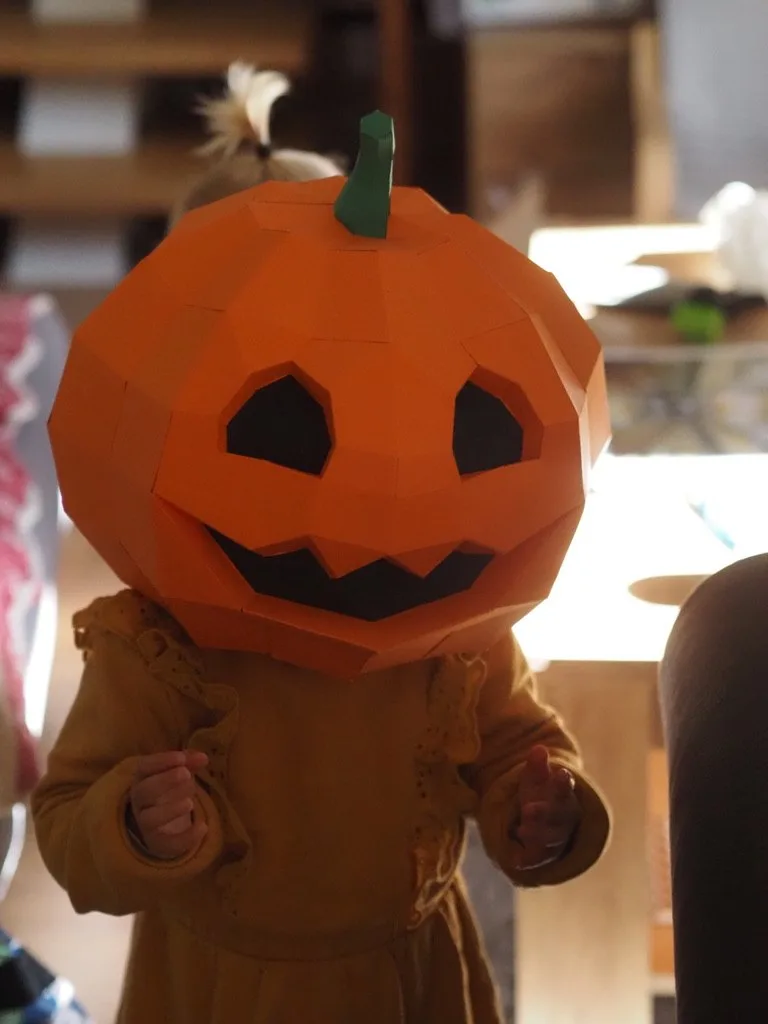 Enfant portant une tête de citrouille souriante