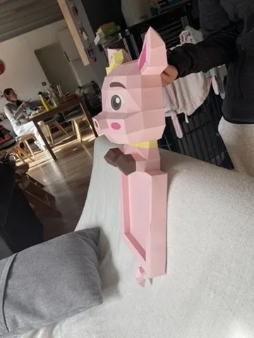 Cochon rose couronné jaune tenu à la main de profil