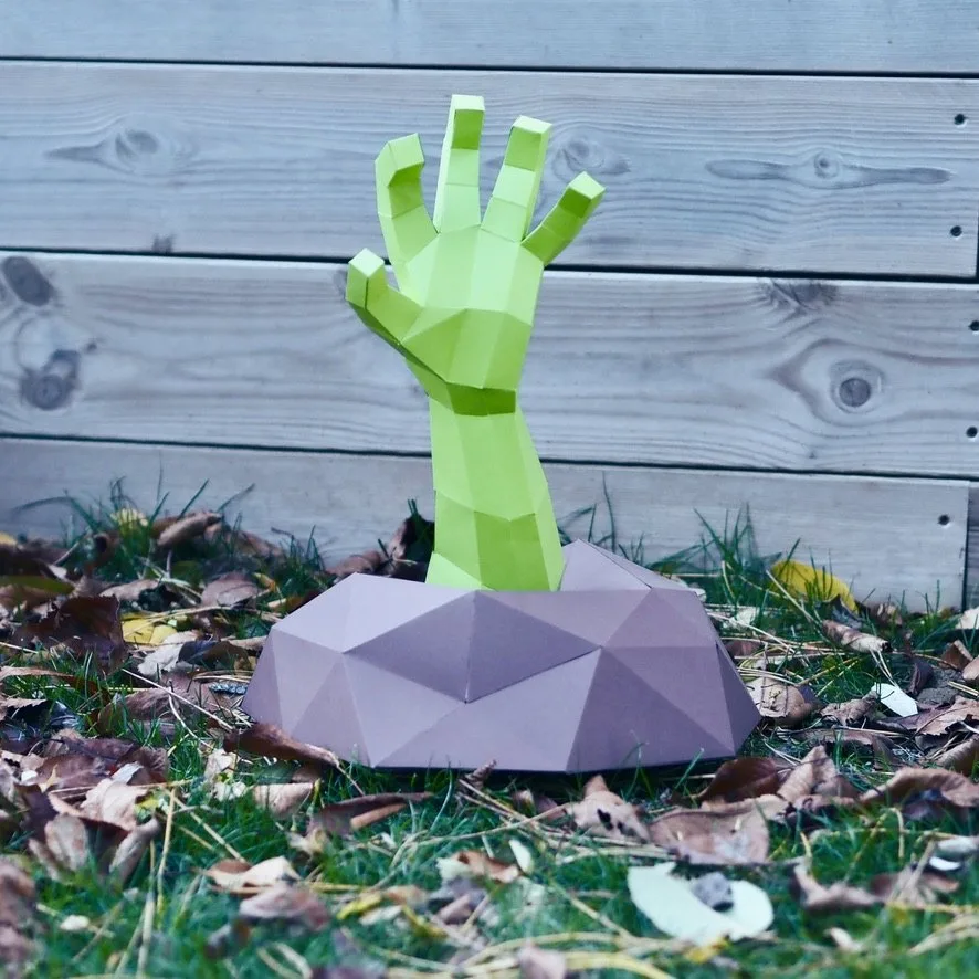 Main verte de zombie sortant d’un rocher sur l’herbe