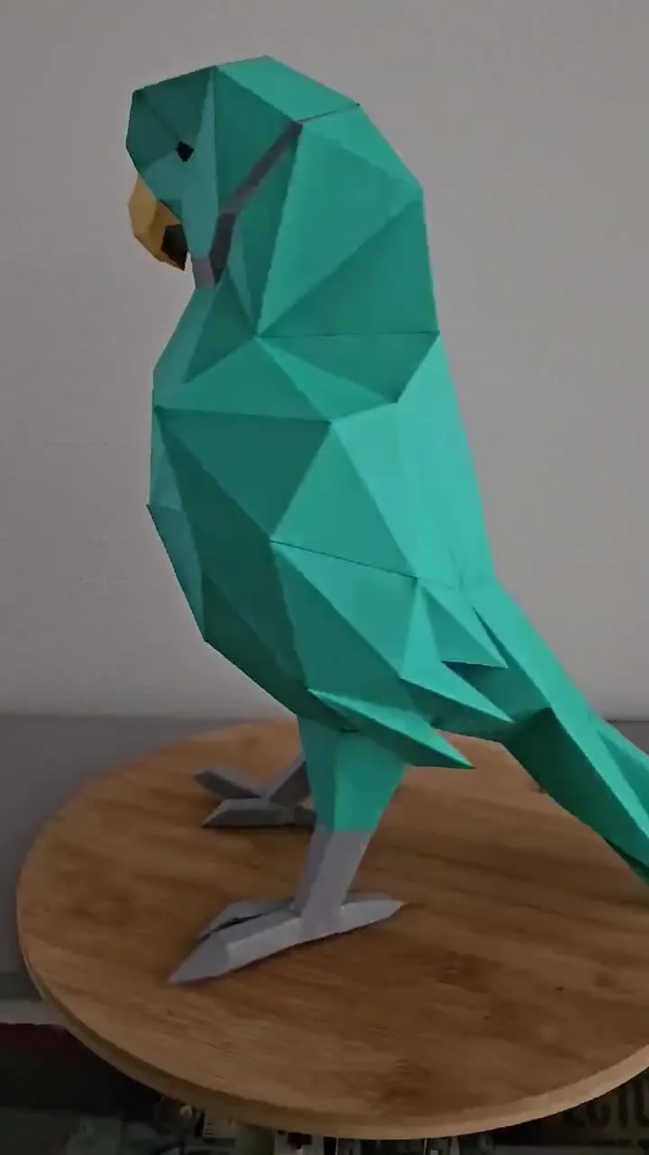 Perroquet vert en papercraft posé sur une table ronde