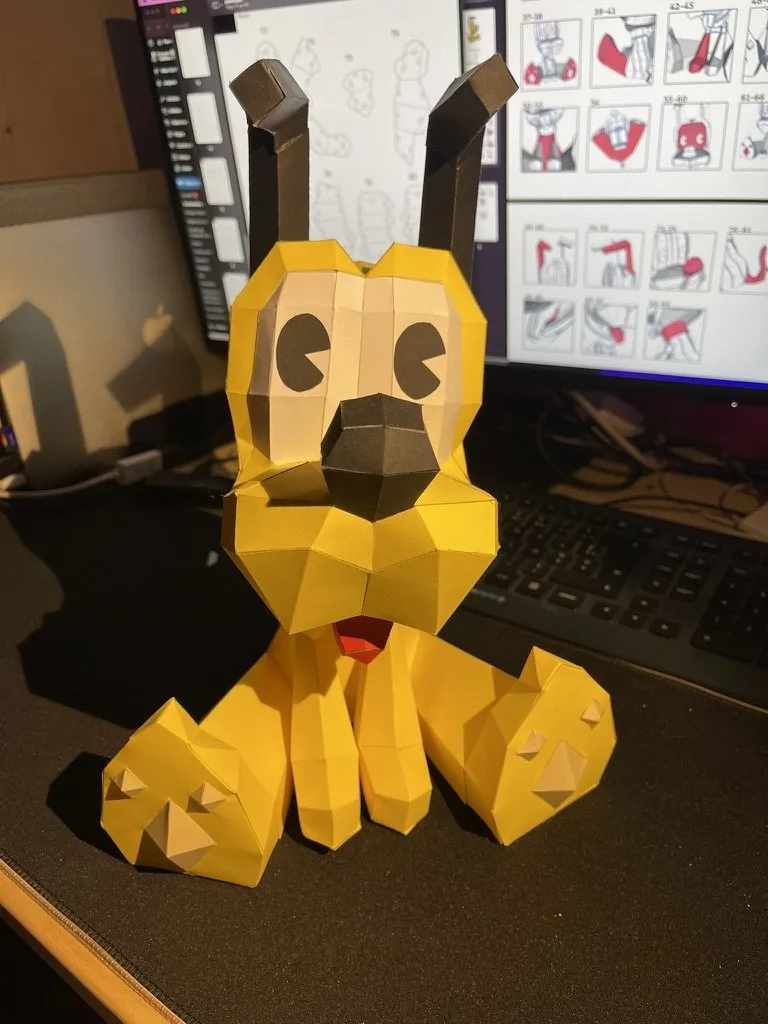 Pluto en origami assis de face sur un bureau