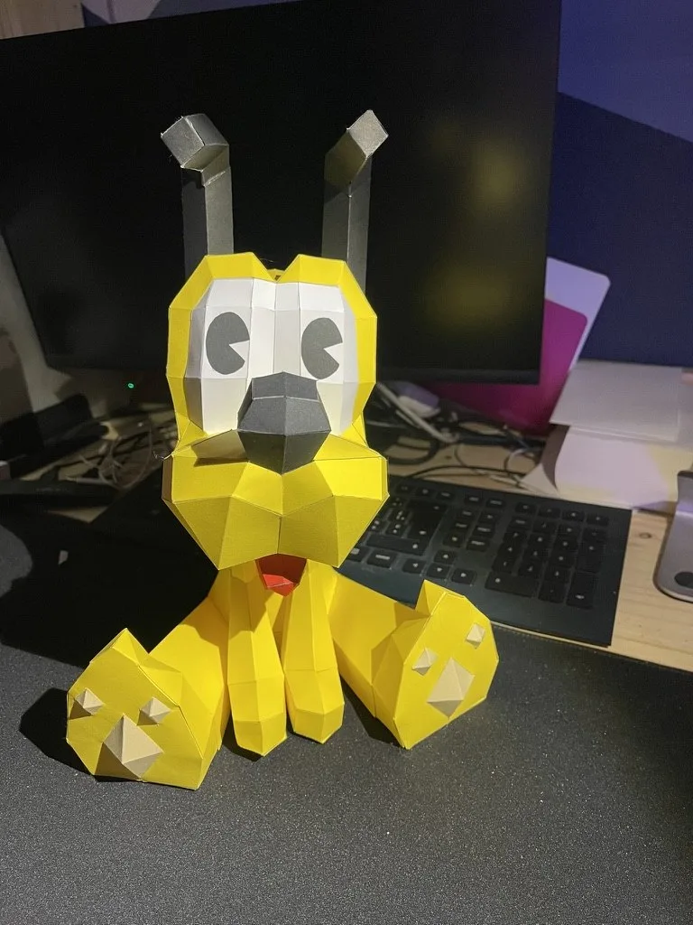 Pluto en origami posé sur un bureau oreilles dressées