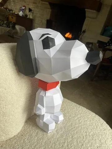 Snoopy blanc sur fauteuil devant cheminée avec collier rouge