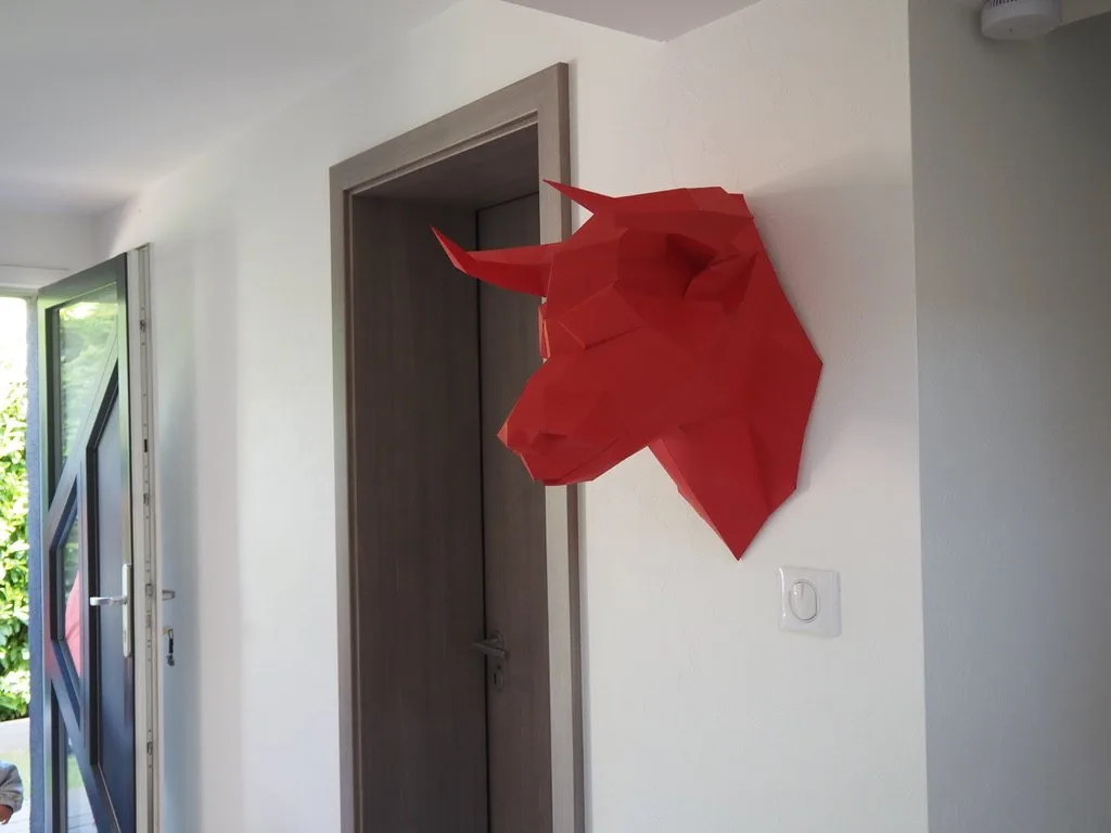 Profil de taureau rouge en papier sur un mur clair