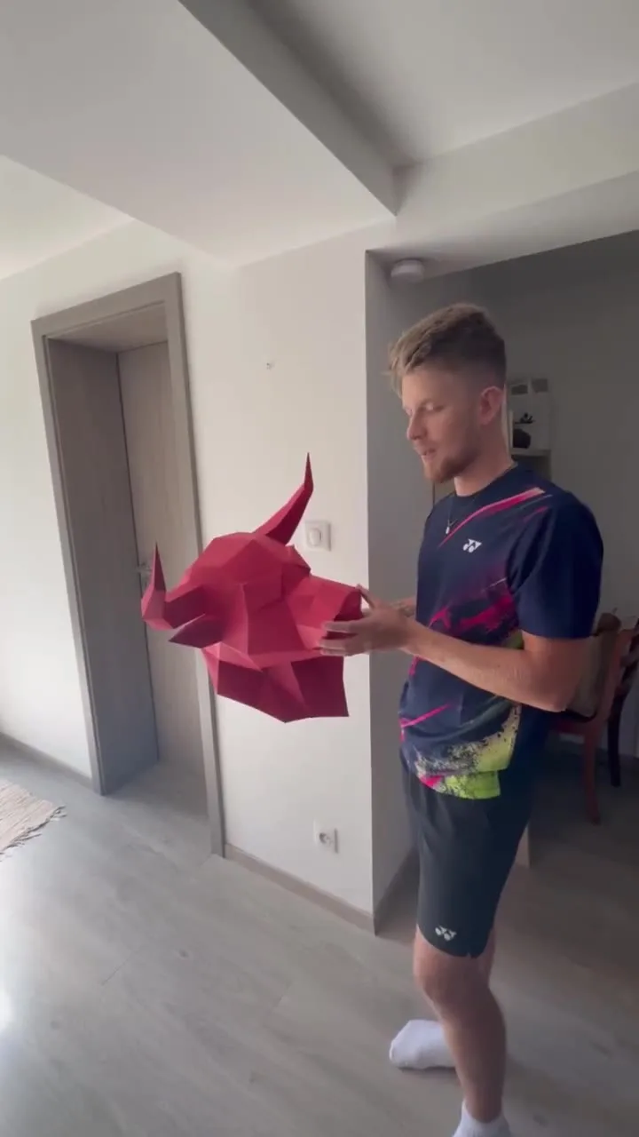 Main tenant une tête de taureau rouge en papier