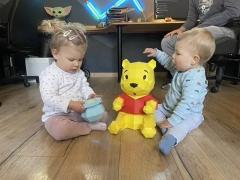 Winnie entouré d’enfants tenant un pot de miel entre ses pattes