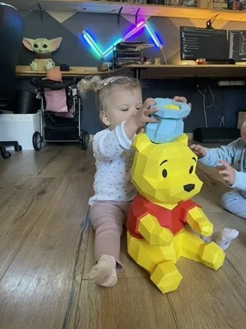 Fillette posant un pot de miel sur la tête de Winnie en papier