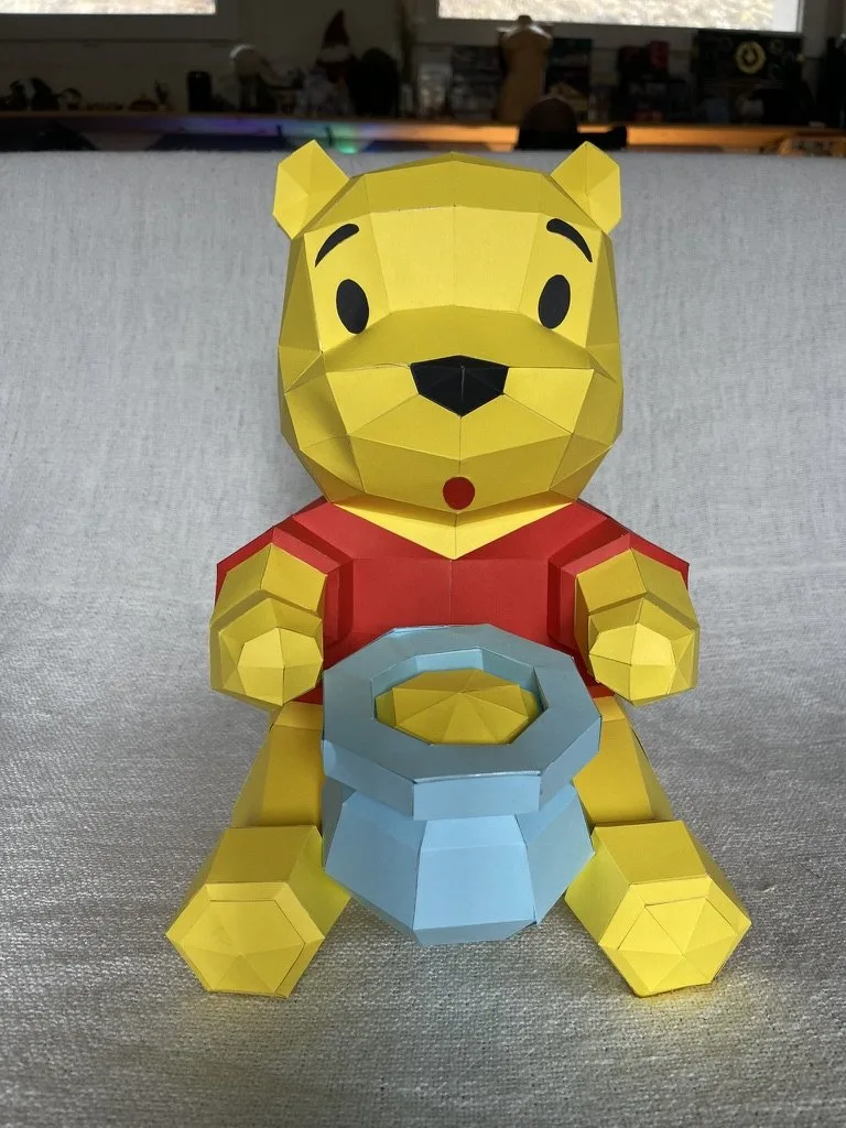 Winnie l’ourson rouge et jaune tenant un pot de miel bleu