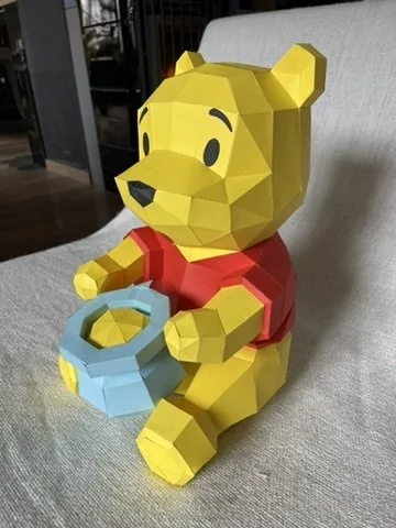 Winnie assis avec son pot de miel bleu entre ses pattes avant