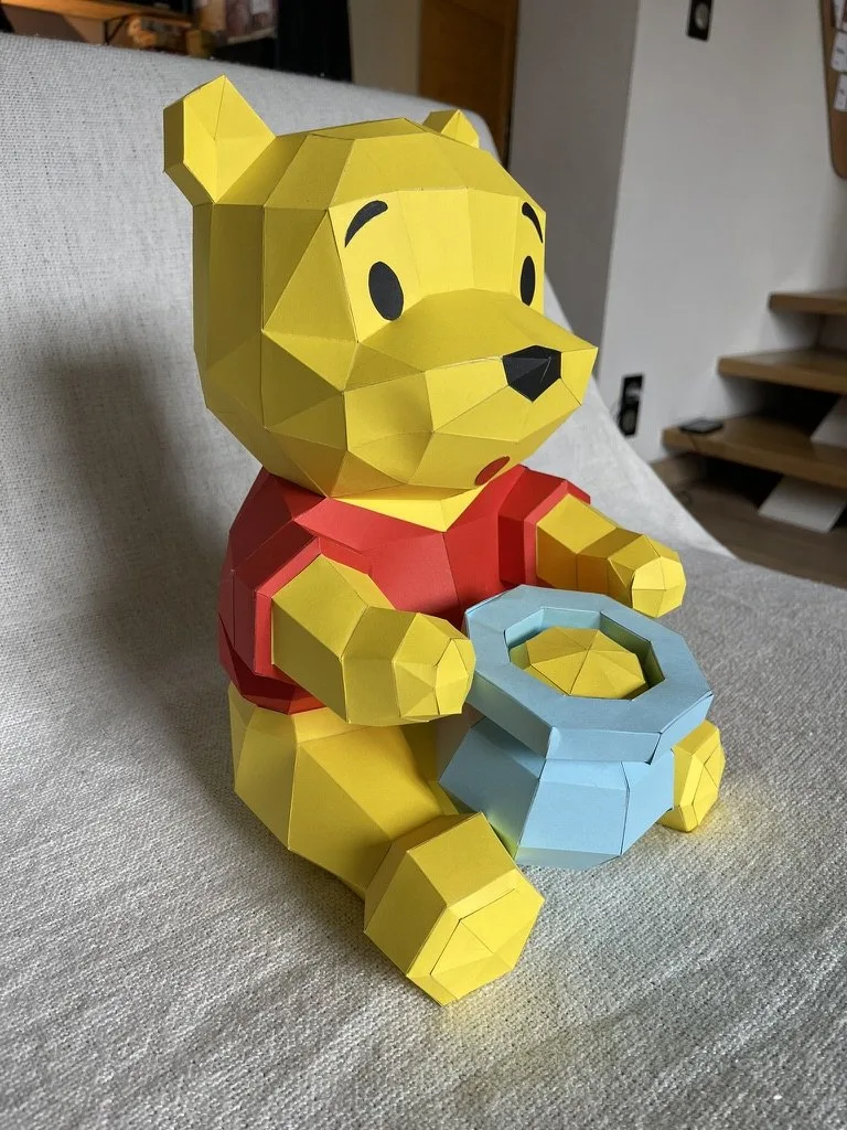 Winnie l’ourson en papier confortablement installé sur un canapé