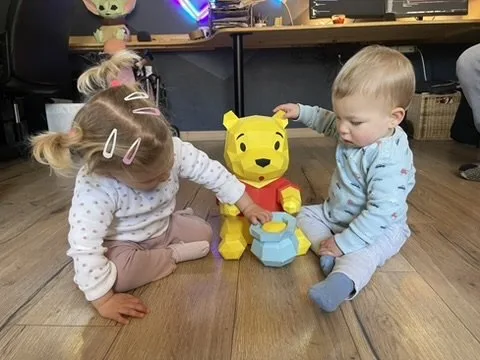 Winnie jaune partageant un moment avec deux enfants souriants