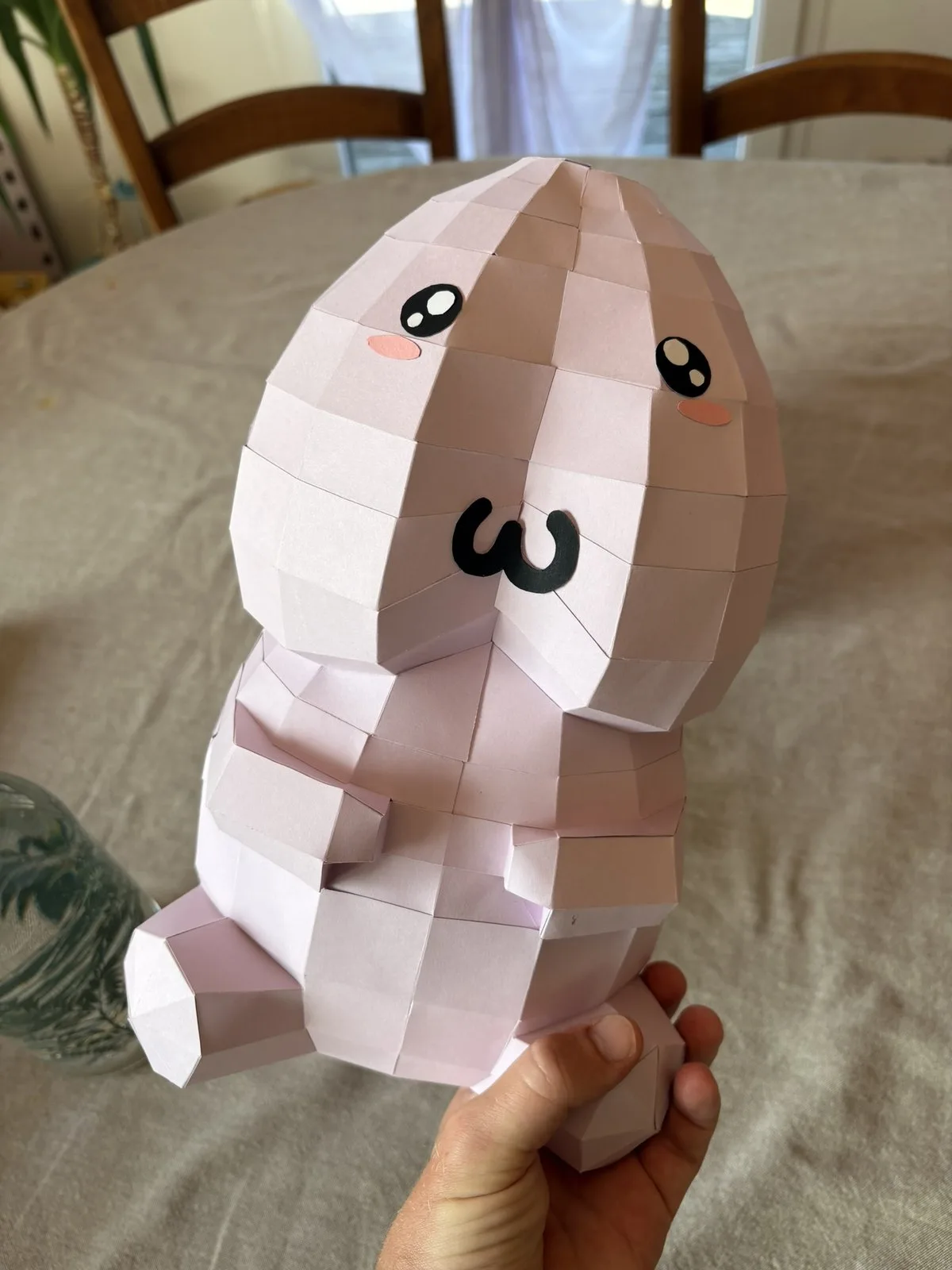 Pénis kawaii rose tenu en main au-dessus d’une table