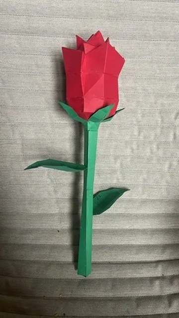 Rose en papier rouge à tige verte sur un canapé