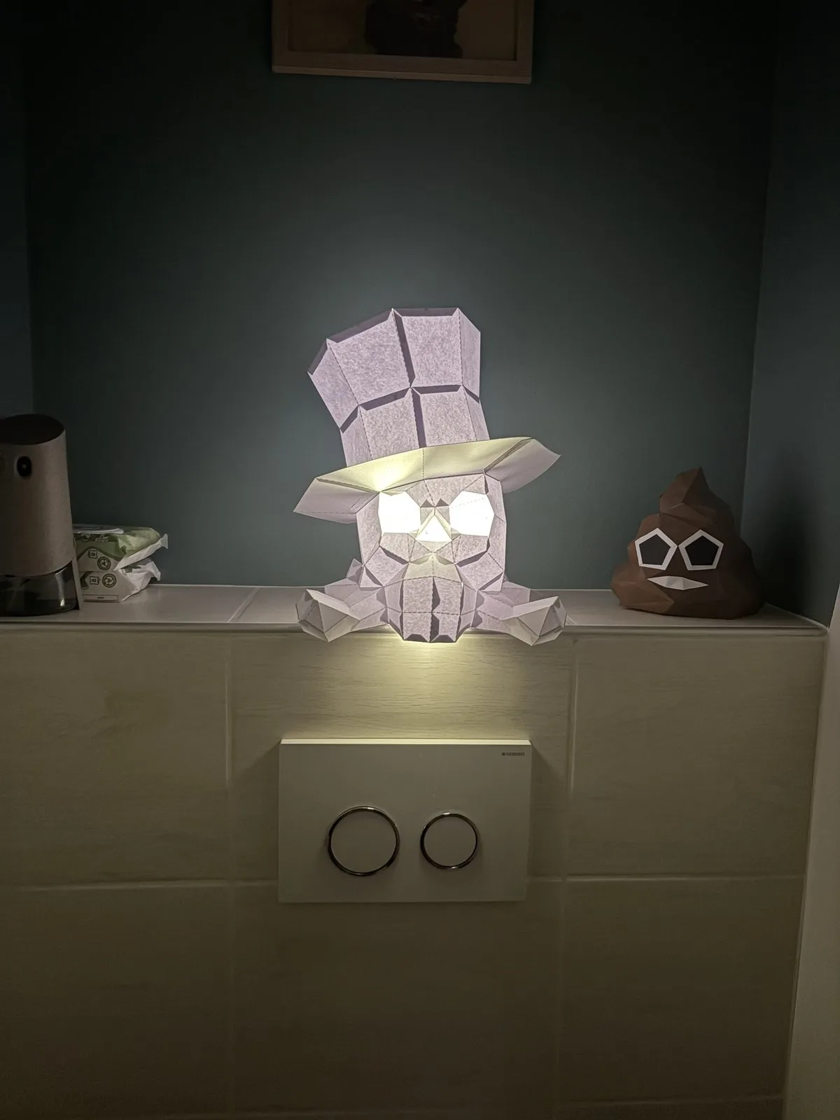 Crâne papercraft éclairé trônant près d’un emoji caca